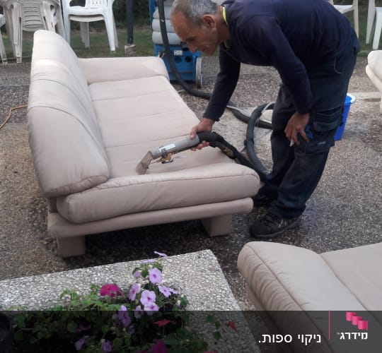 אדם מנקה ספה עם מכשיר ניקוי מקצועי